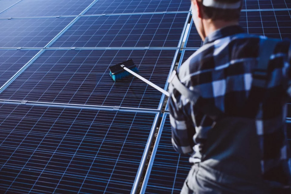 Person cleaning solar panels with a soft cloth and water